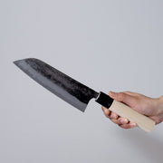 Hand holding a Nakamura Hamono Kurouchi Santoku Knife 165mm