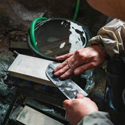 Closeup of the hands of Hidetoshi Miwa, master artisan of Miwa Hamono, polishing a blade