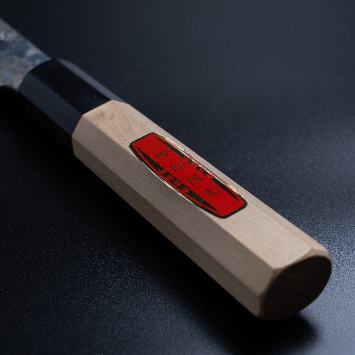 Closeup of the wooden handle with maker red label for the Shirou Kunimitsu Special White Steel Kurouchi Gyuto Knife 210mm