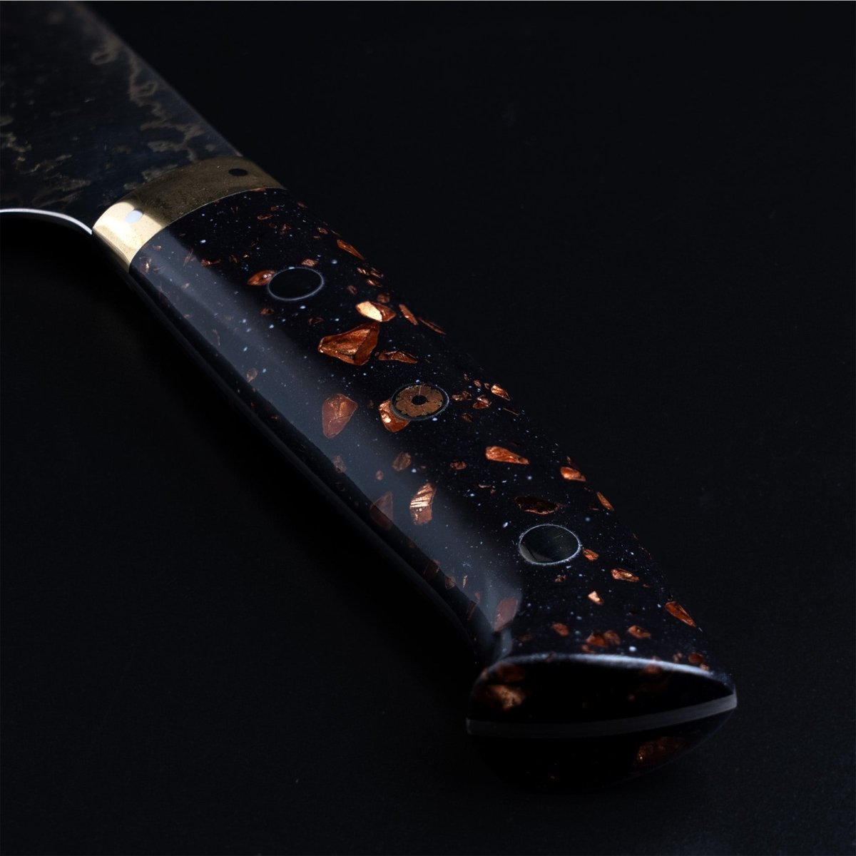 Closeup on black and brown Corian handle on Takeshi Saji VG-10W Stainless Steel Gyuto 230mm on a dark background