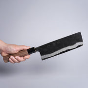 Hand holding Kyohei Shindo Kurouchi Nakiri 170mm crafted from Aogami 2 in Kochi, Japan on grey background
