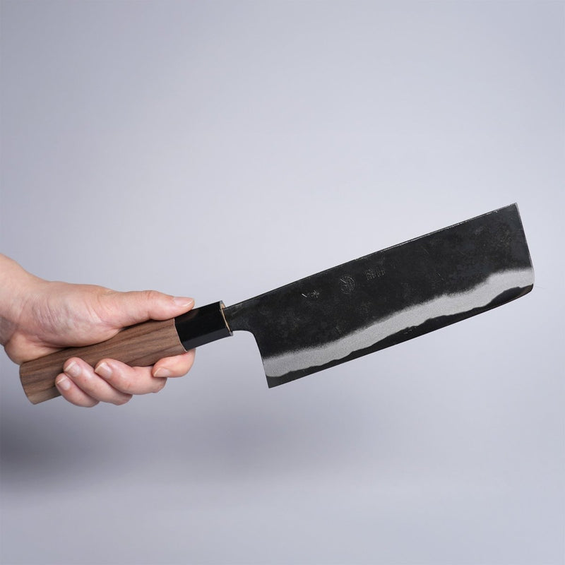 Hand holding Kyohei Shindo Kurouchi Nakiri 170mm crafted from Aogami 2 in Kochi, Japan on grey background