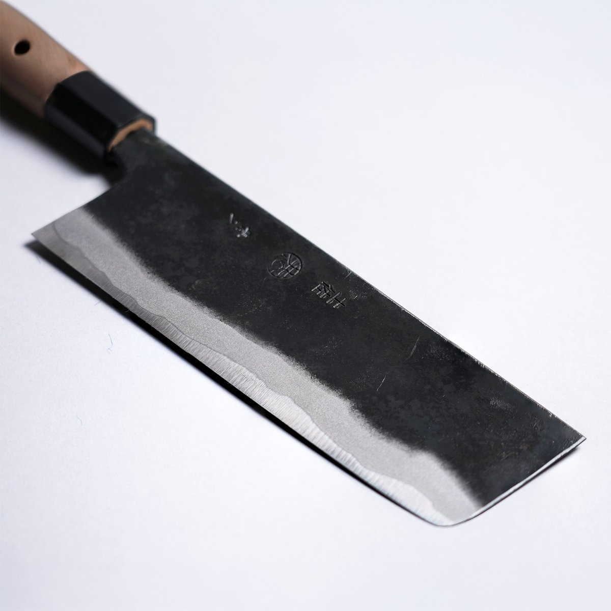 Closeup on tip of Kyohei Shindo Kurouchi Nakiri 170mm crafted from Aogami 2 in Kochi, Japan on grey background