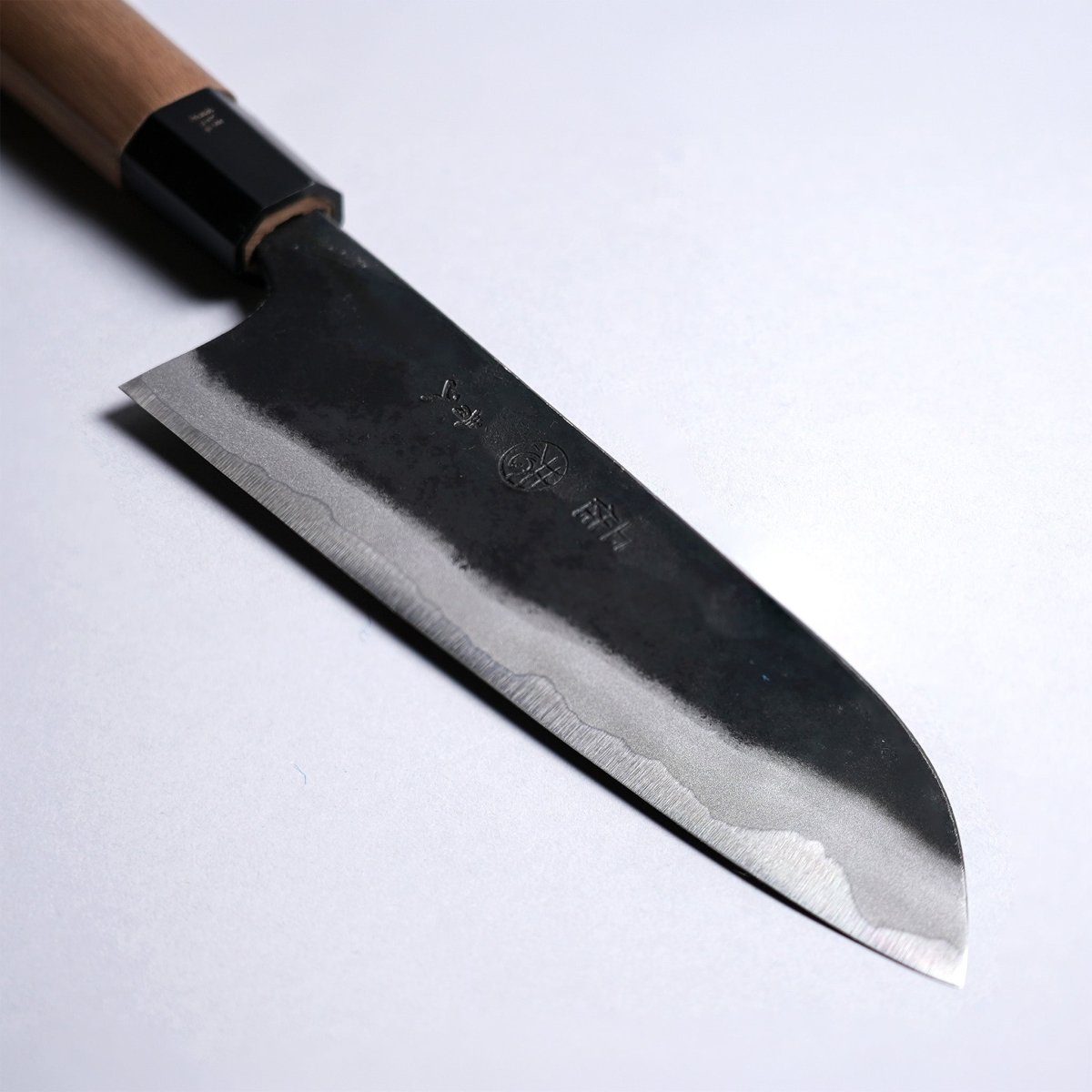 Closeup on tip of Kyohei Shindo Kurouchi Santoku 170mm crafted from Aogami 2 in Kochi, Japan on grey background