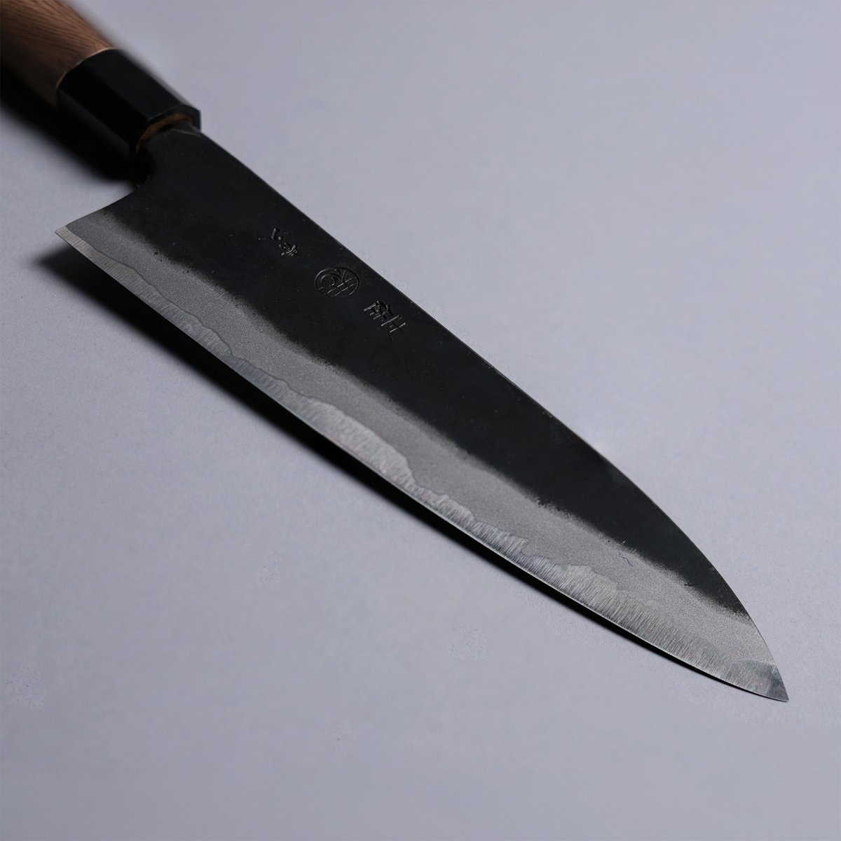 Closeup on tip of Kyohei Shindo Kurouchi Gyuto 220mm crafted from Aogami 2 in Kochi Japan on grey background