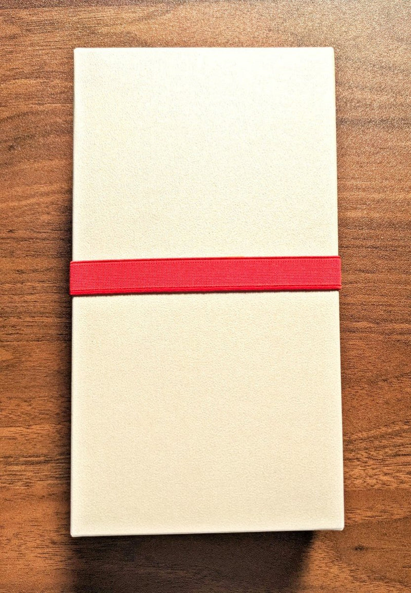 Closed box of the 'Happa' Leaf Shaped All - Around Knife by Asano Blacksmith in beige with a red strap around