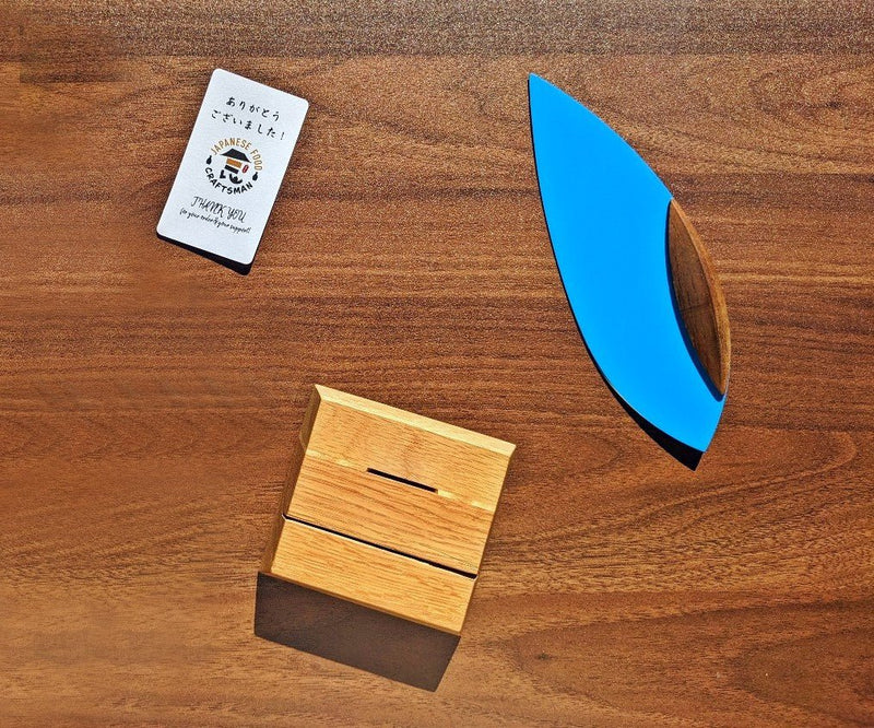 'Happa' Leaf Shaped All - Around Knife by Asano Blacksmith in blue next to its dedicated stand and a Japanese Food Craftsman thank-you card from an above perspective