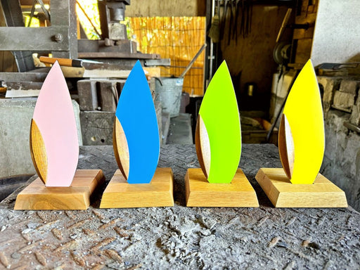 The 4 variations of the 'Happa' Leaf Shaped All - Around Knife by Asano Blacksmith (pink, blue, green and yellow) on each of their respective stands and aligned next to each other in the workshop