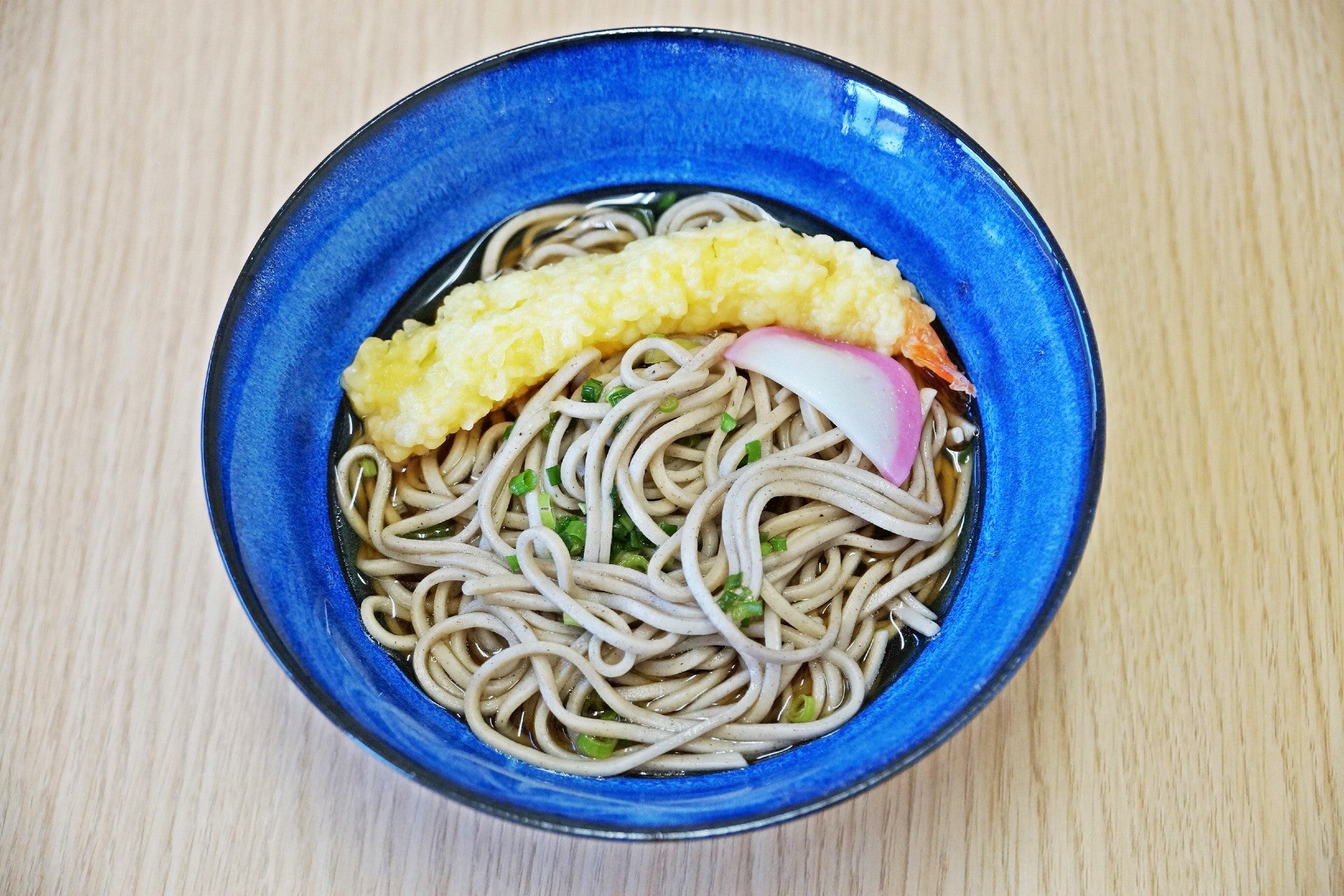 Soba and fried shrimp in a blue bowl.