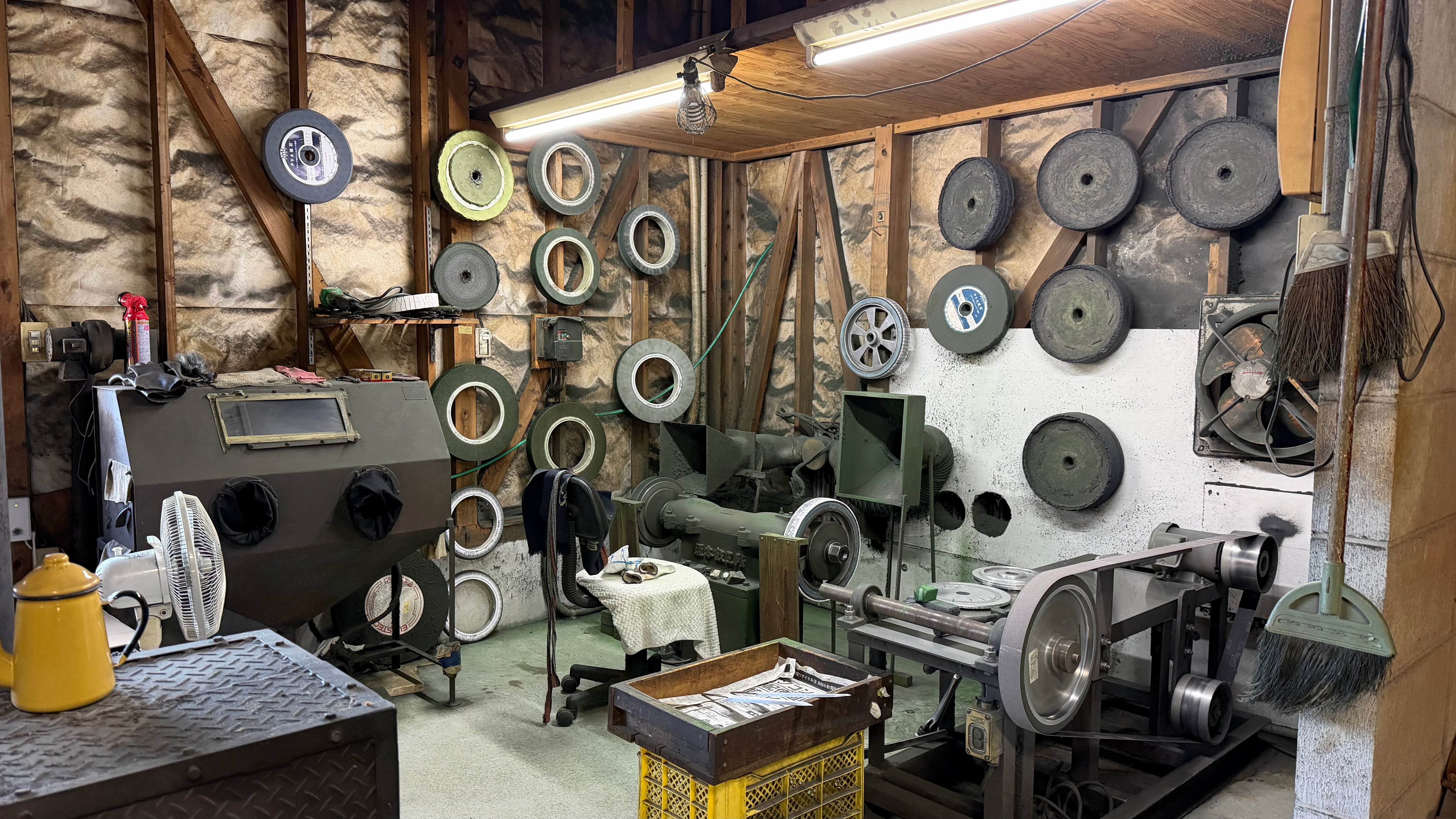 A corner of Tadokoro Hamono workshop with buffer, polishing and grinding wheels hanging on the walls