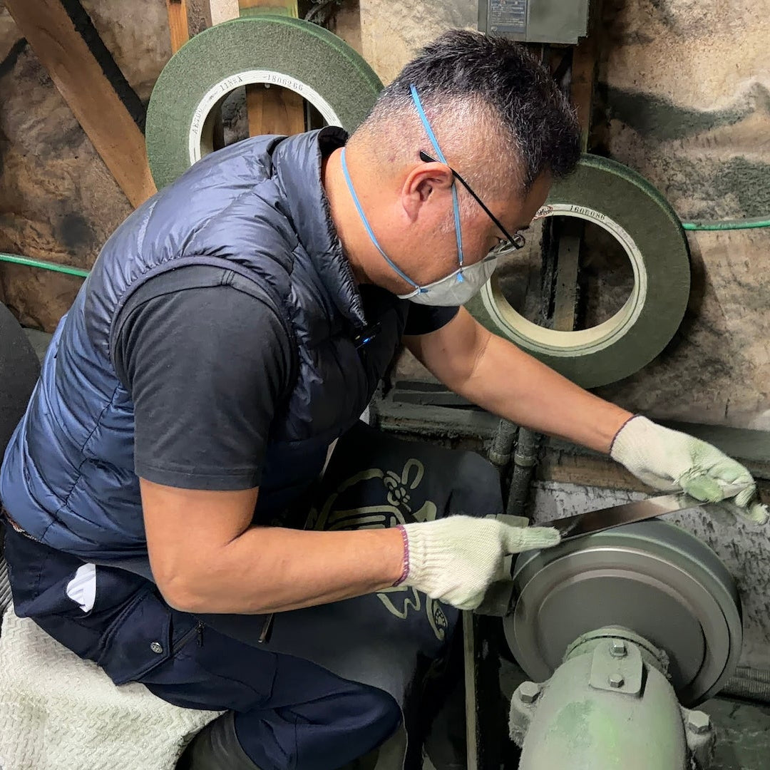Makoto Tadokoro polishing a blade in his workshop with a safety mask
