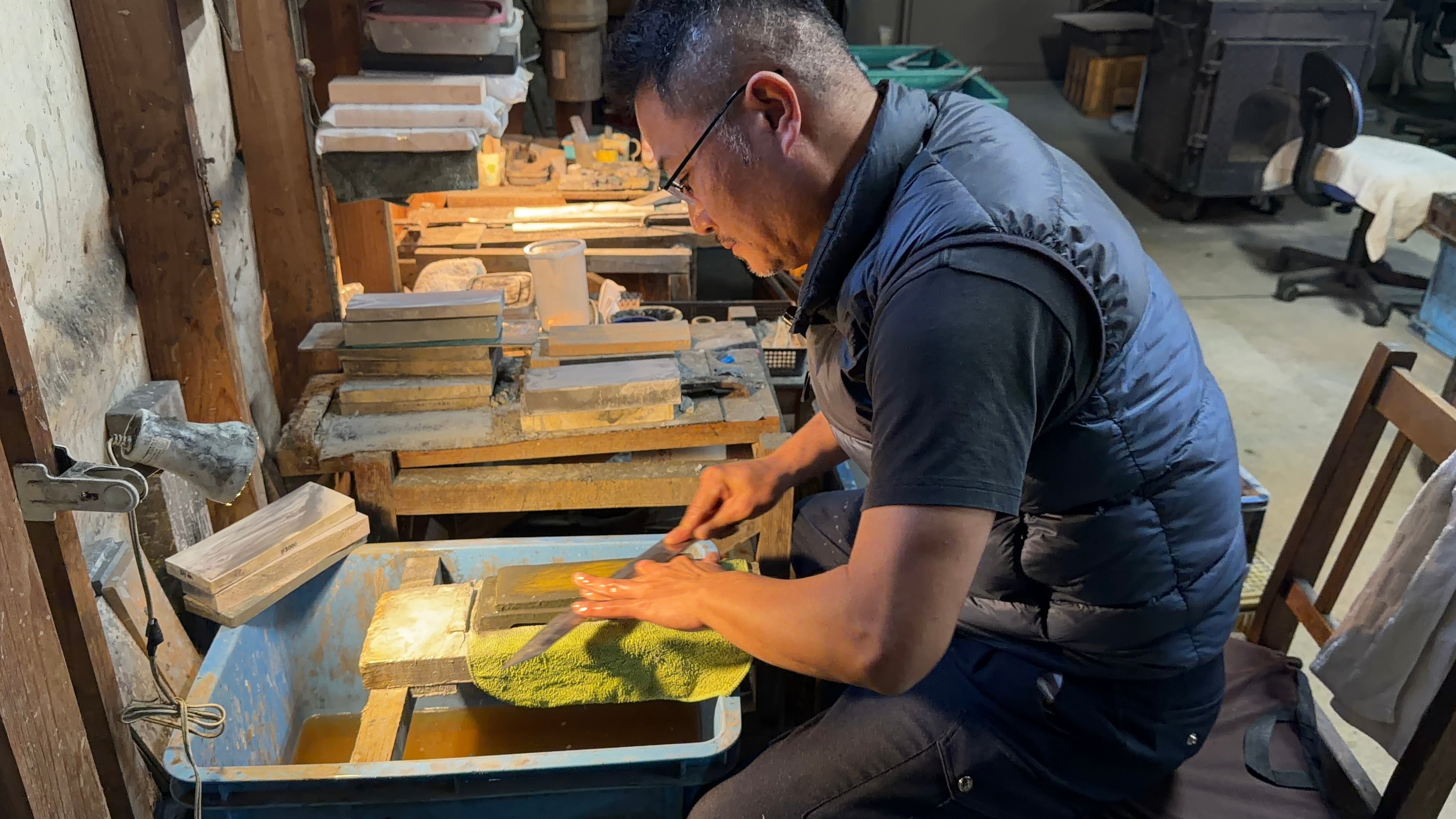 Makoto Tadokoro from Tadokoro Hamono seated while sharpening a blade