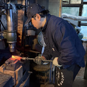 Kajihara Hamono craftsman hammering a hand-forged Japanese knife in their workshop