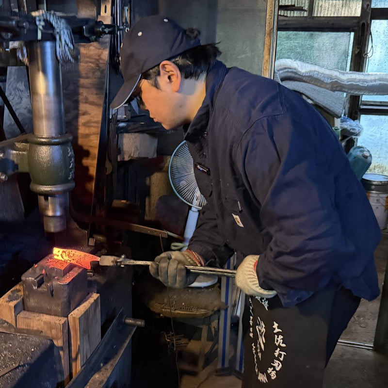 Kajihara Hamono craftsman hammering a hand-forged Japanese knife in their workshop
