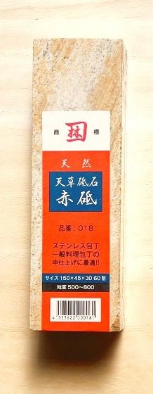 Natural red sharpening stone included with Yamawaki Hamono knives on tan background