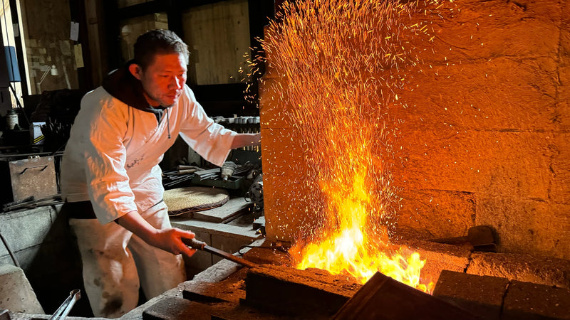 Asano Blacksmith artisan heating metal in the forge fire