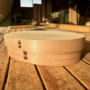 Closed Oval Bento Box crafted by Hakata Bentwood Tamaki on wooden background outdoors