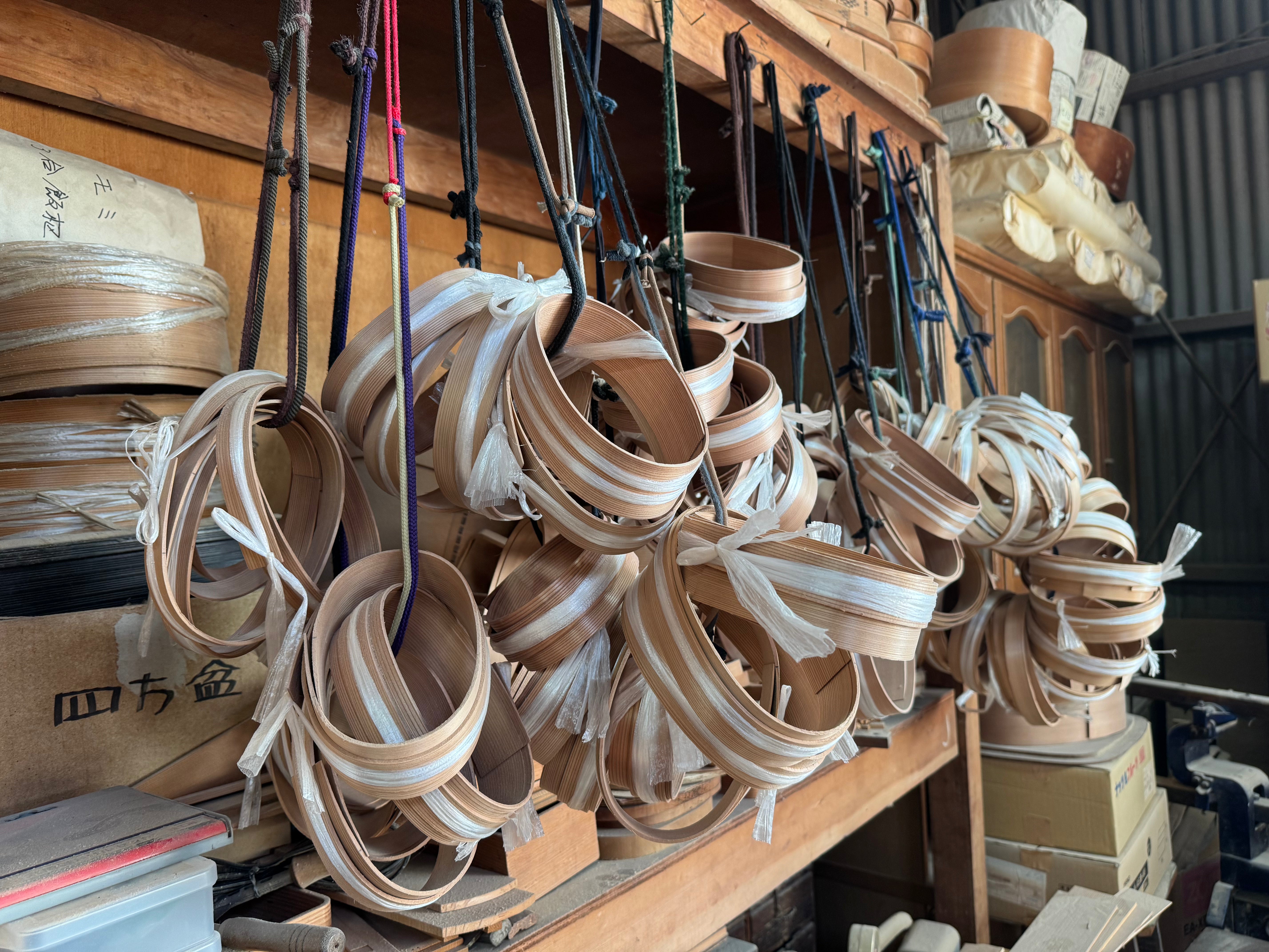 Wooden frames for Magewappa Oval bento boxes hanging inside the Hakata Bentwood Tamaki workshop