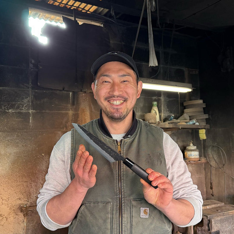 蓑毛鍛冶 黒打青紙2号切付 牛刀包丁170mmを手に微笑む蓑毛鍛冶の名匠の肖像