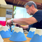 Craftsman from Imari Togeit painting Ceramic Coffee Filter COFIL Mt. Fuji with finished and unfinished filters in the foreground