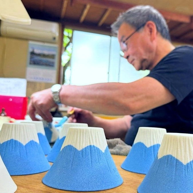 Craftsman from Imari Togeit painting Ceramic Coffee Filter COFIL Mt. Fuji with finished and unfinished filters in the foreground