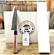 Kurouchi Gyuto Kitchen Knife 180mm crafted by Kawasaki Blacksmith leaning on white box on wooden table