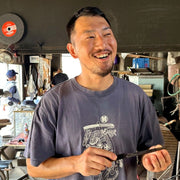 The youngest member of the Minomo Blacksmith family smiling and holding a knife