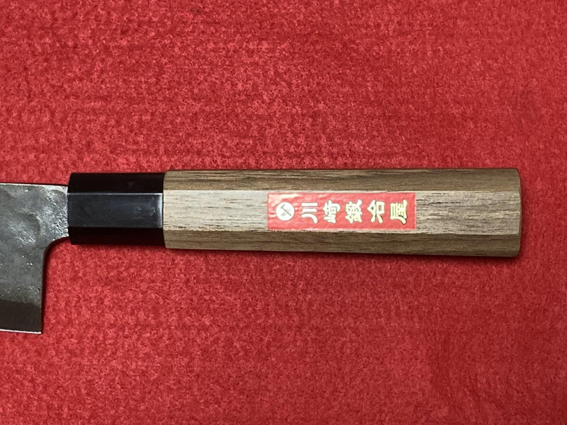 Closeup on handle of Kurouchi Gyuto Kitchen Knife 180mm crafted by Kawasaki Blacksmith on red background