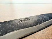 Closeup of an engraved blade of a Minomo Blacksmith Santoku Knife in Japanese characters