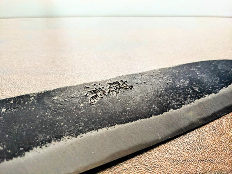Closeup of an engraved blade of a Minomo Blacksmith Santoku Knife in Japanese characters