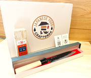 Minomo Blacksmith Santoku Knife open box with blade inside next to Amakusa Red Sharpening Stone, branded shipping box from Japanese Food Craftsman and thank-you cards