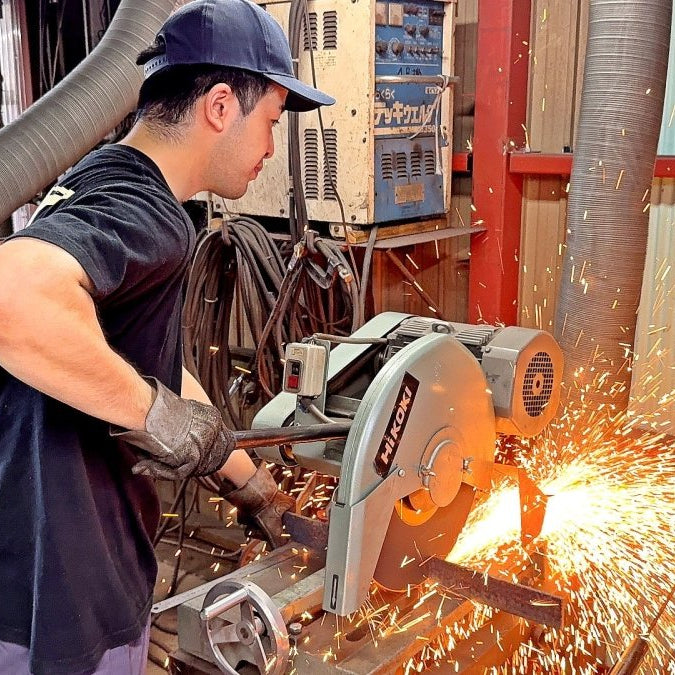Nigara Hamono craftsman working in the workshop while sparks are flying when cutting the blade