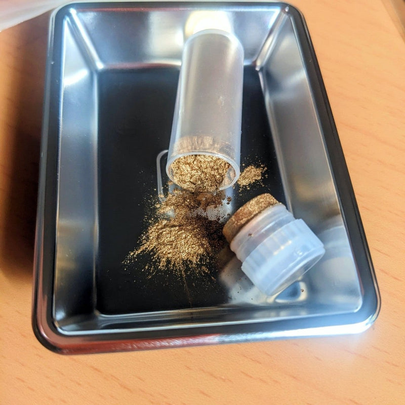 Closeup on gold power included in Kintsugi Repair Kit by Kintsugi Kurashi displayed on metal tin on wooden table