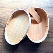 Empty Oval Bento Box crafted by Hakata Bentwood Tamaki open showing inside of lid on wooden background