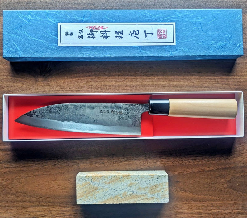 Kurouchi Deba Knife 21cm by Nakamura Hamono inside the open box with red sharpening stone next to it