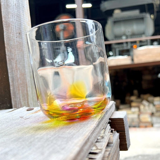 Handcrafted Rainbow Rocks Glass by Soejima Glassware on wooden table with workshop in the background