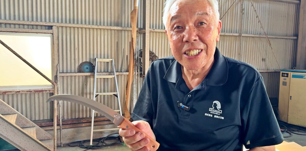 Seki Kikusui Craftsman smiling while holding Multi-Purpose Sickle in his workshop in Seki, Japan