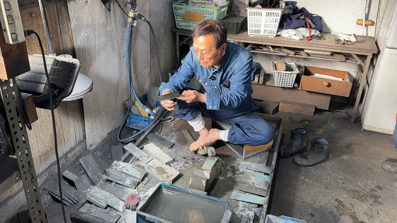 Bizen Osafune Swordsmith master artisan examining a knife's blade in his workshop