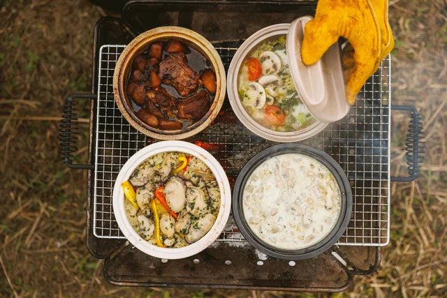 Four dishes in pots are placed on a bbq grill.