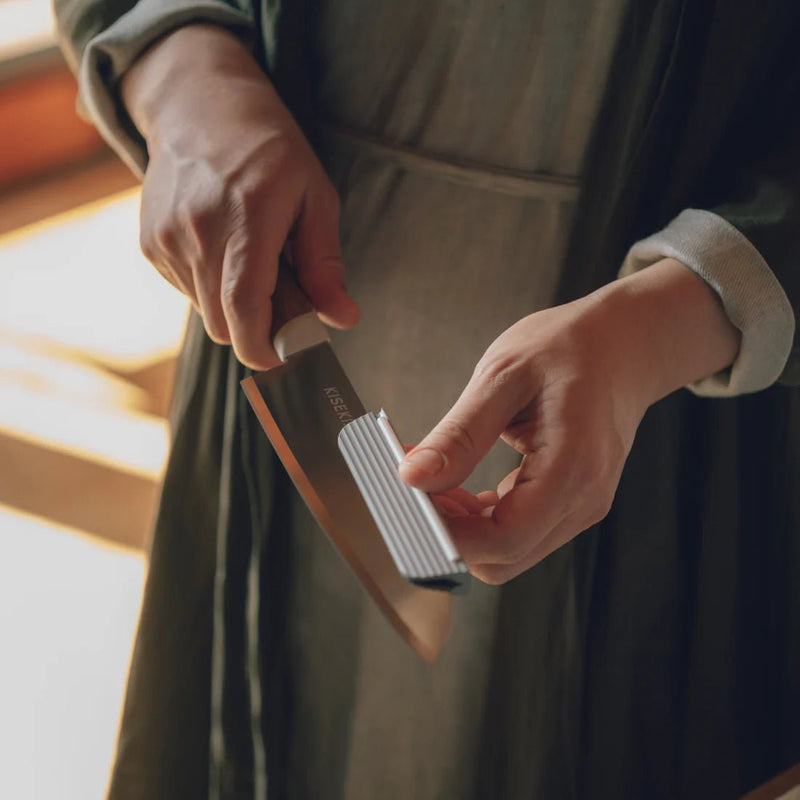 Closeup of hands using the KISEKI Knife Attachment for Sharpening on a KISEKI Santoku Knife