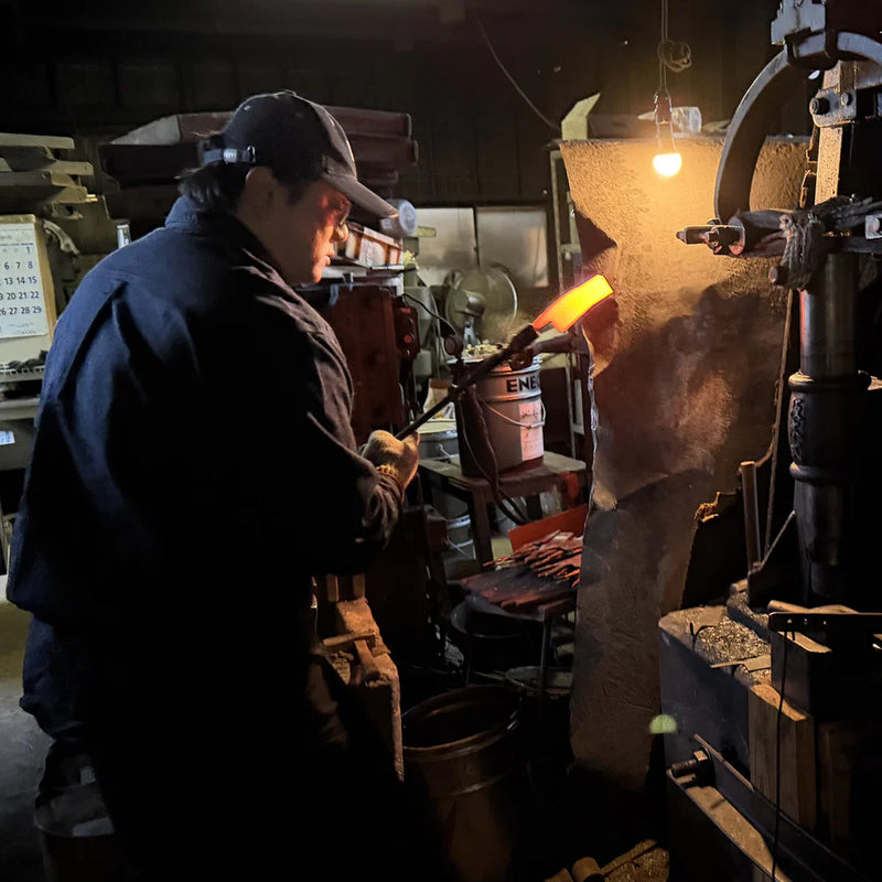 Kajihara Hamono master artisan hammering a heated blade.