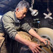 Toshio Nakamura's son and apprentice inside Nakamura Blacksmith's workshop polishing a metal knife blade.