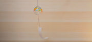 Handcrafted Rainbow Wind Chime by Soejima Glassware hanging vertically in front of light wooden background blowing in the wind