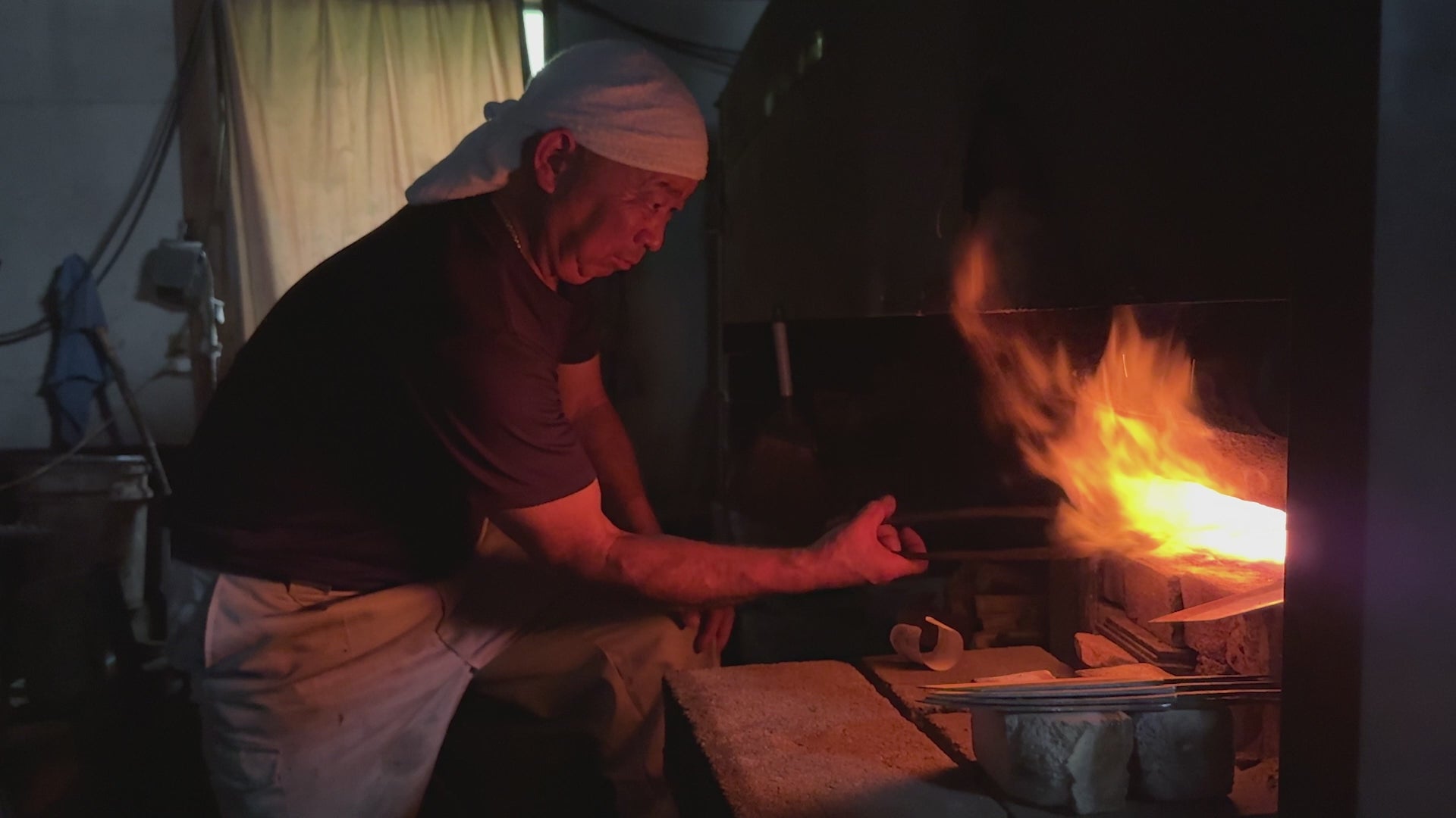 Shigemitsu Hamono master balcksmith heating  a metal blade in the fire inside his workshop