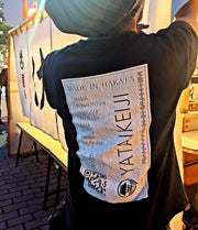 屋台刑事の公式Tシャツを着て屋台の準備をする安倍さんの後ろ姿のアップ